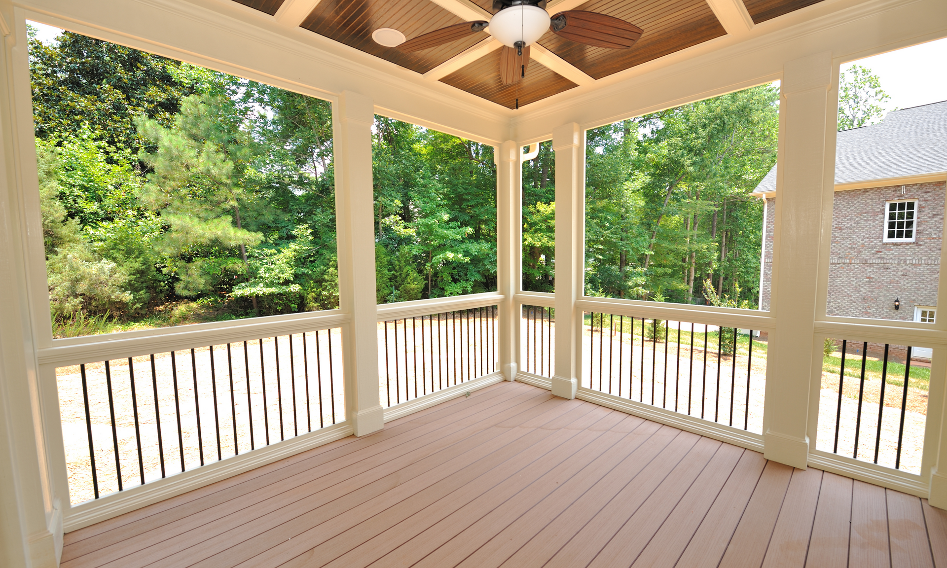 A photo of a deck that has a deck roof installed as well. The Deck is empty and has white railings.