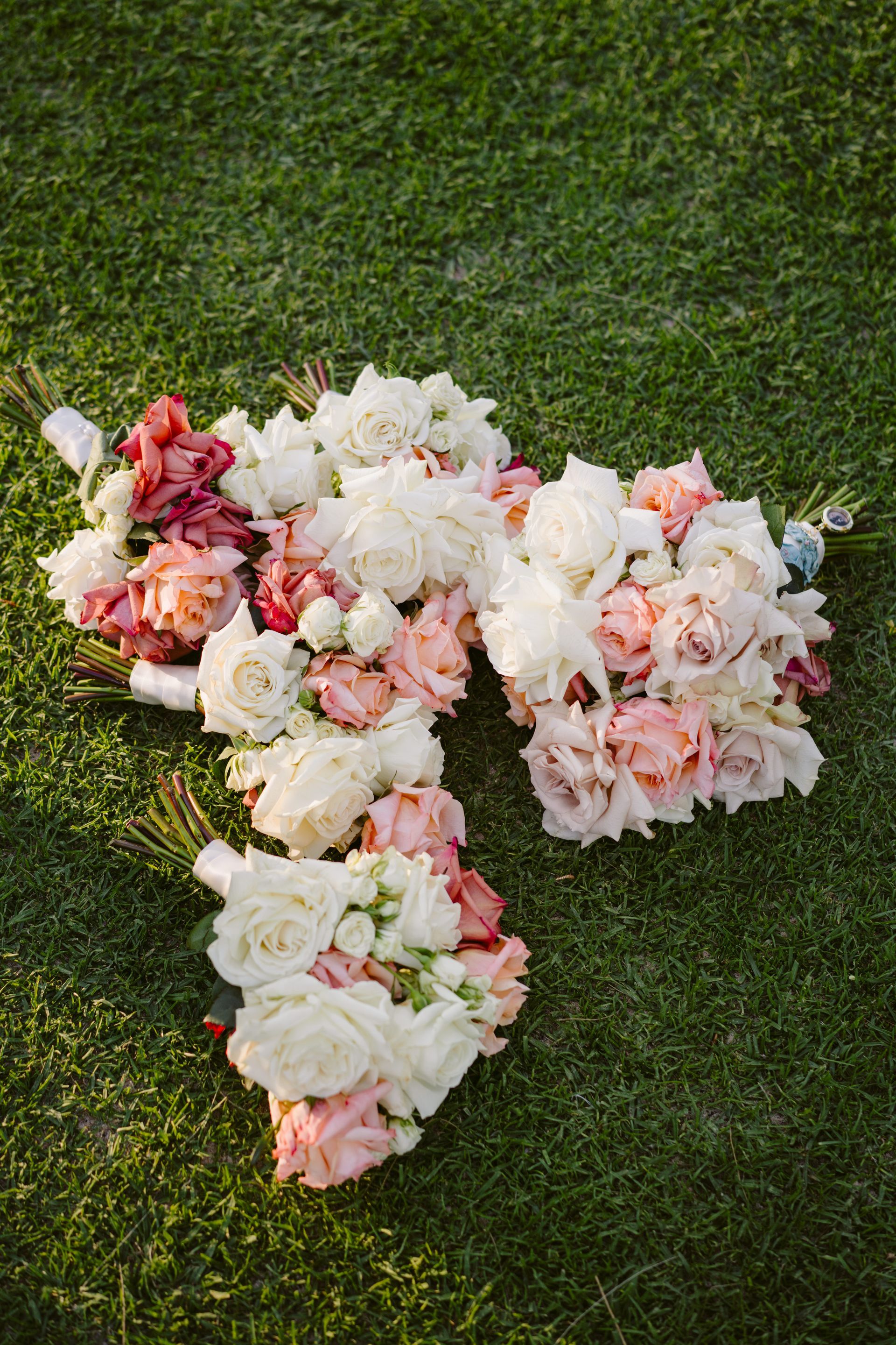 Bouquets of white and pink flowers arranged on green grass.