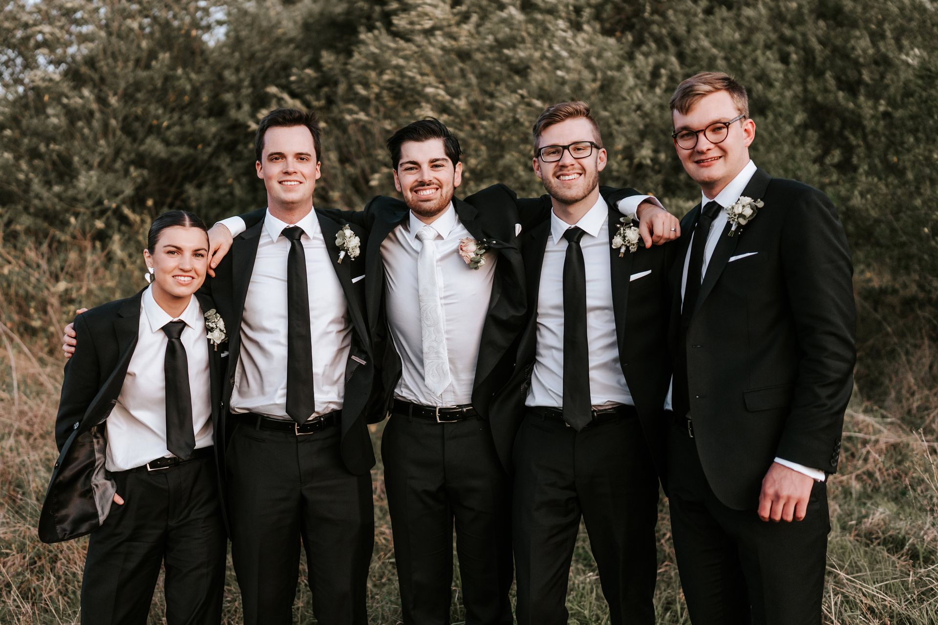 Five people in suits stand together outside.