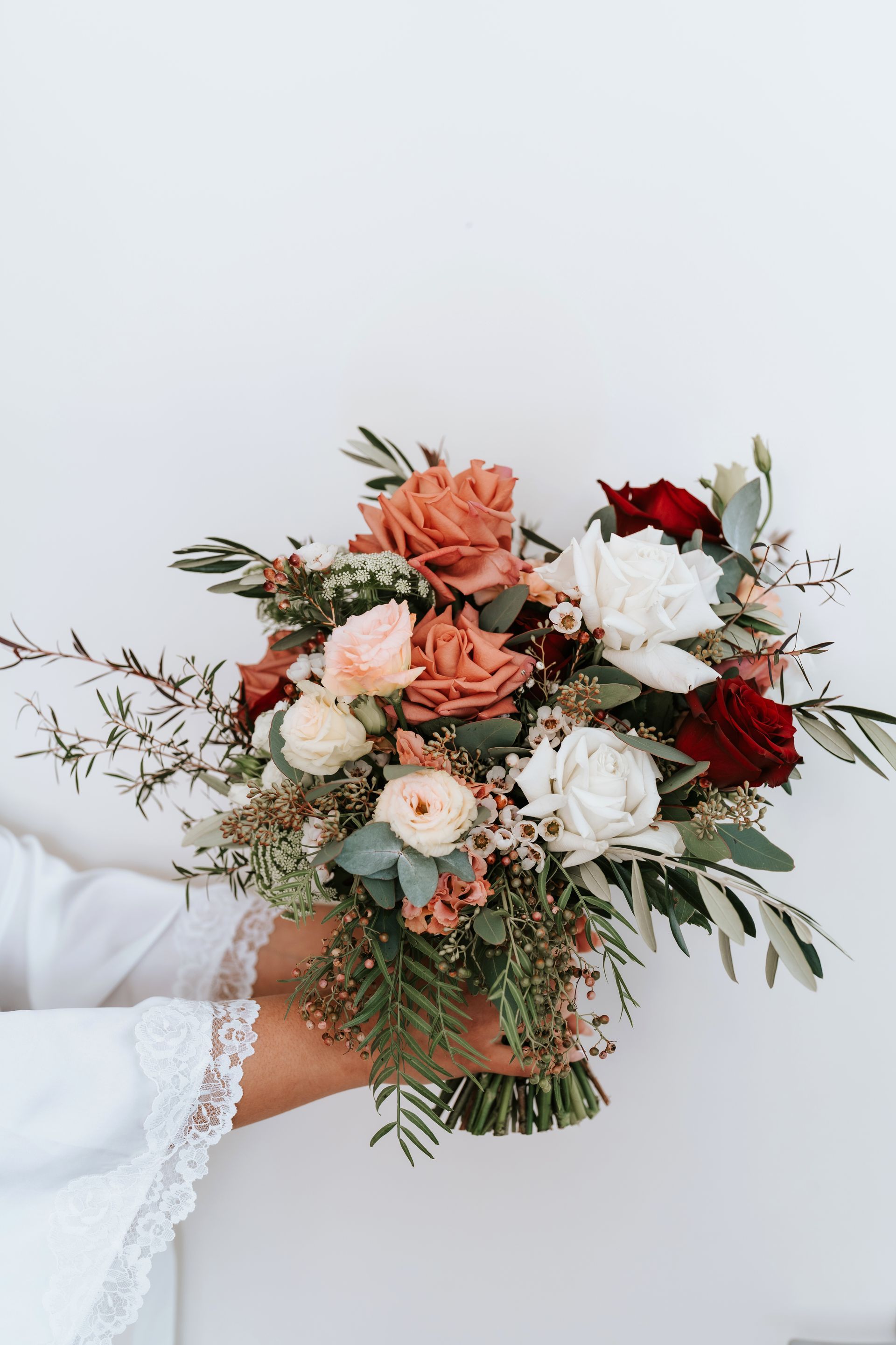 Woman holding a bouquet of colorful roses against a white background.