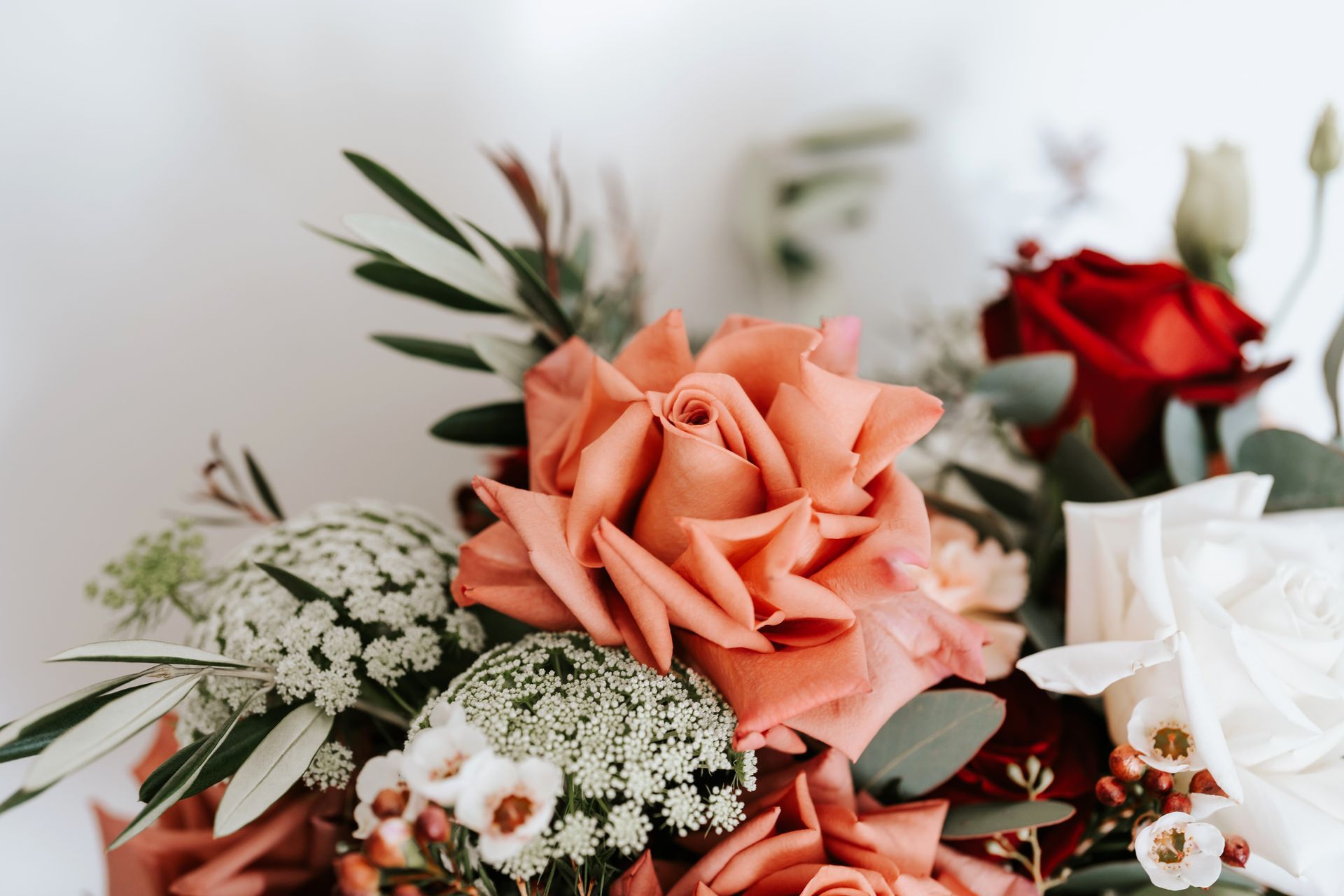 Close-up of a floral arrangement with a large coral rose as the focal point, with red and white blooms.