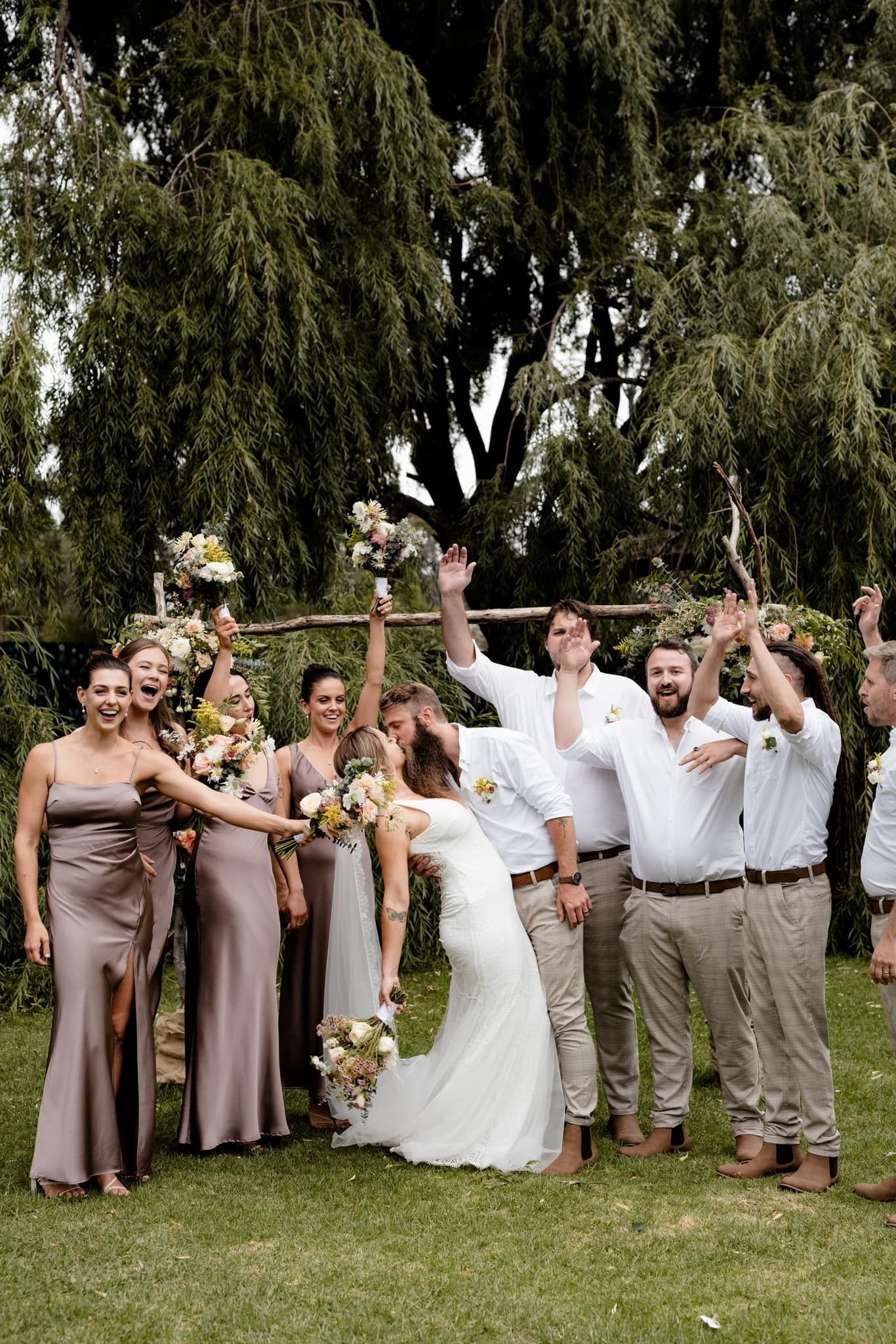 Bride and groom celebrate with bridesmaids and groomsmen in a garden.