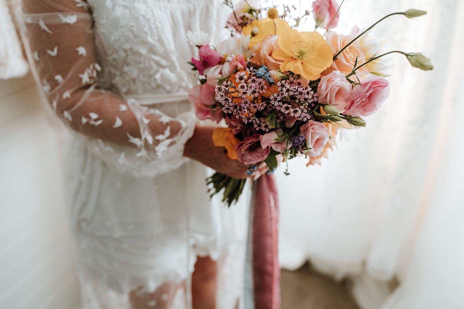 Woman in white dress holding a colorful bouquet of flowers, soft lighting.
