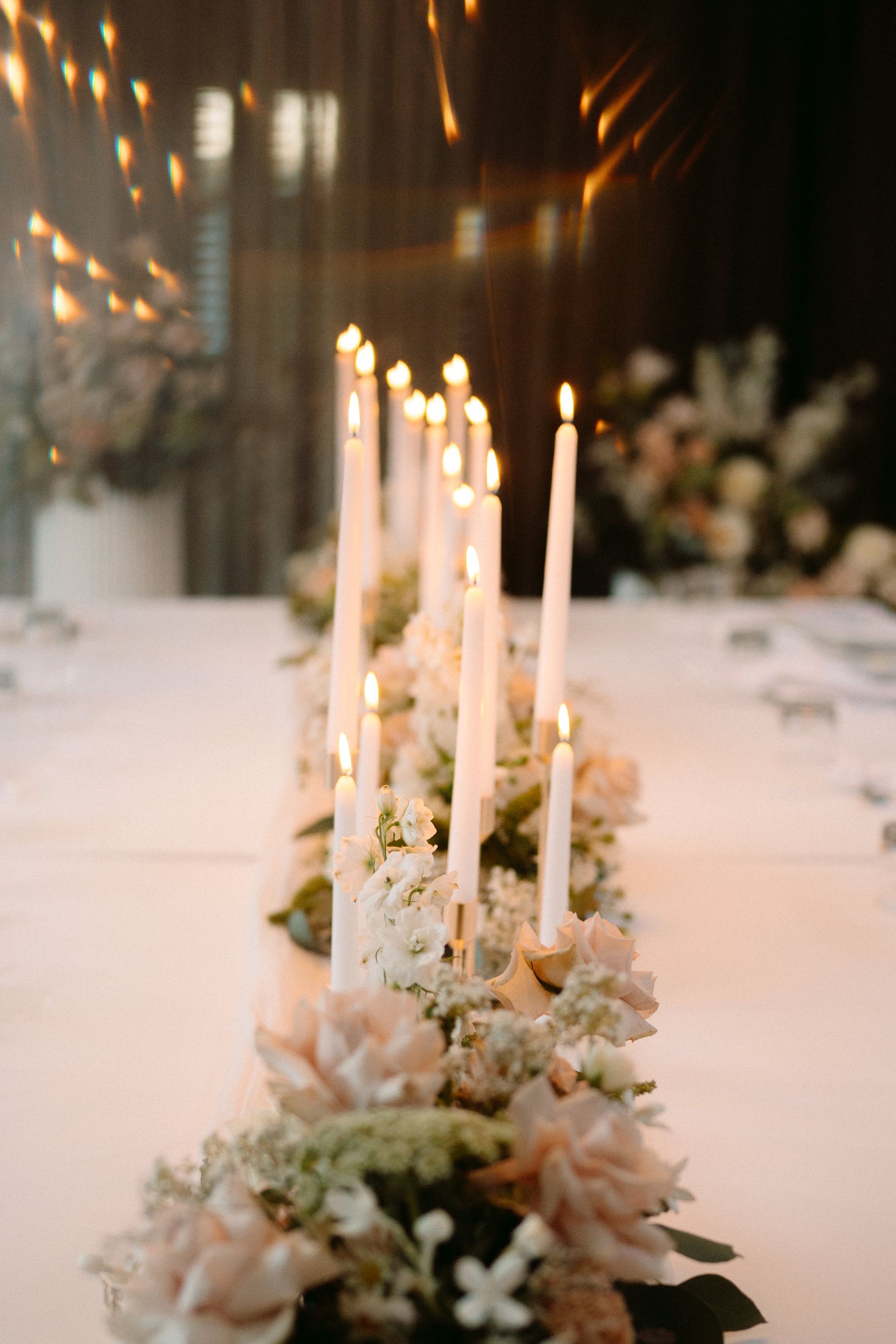 Candles and white flowers center a table, creating a romantic and elegant ambiance.