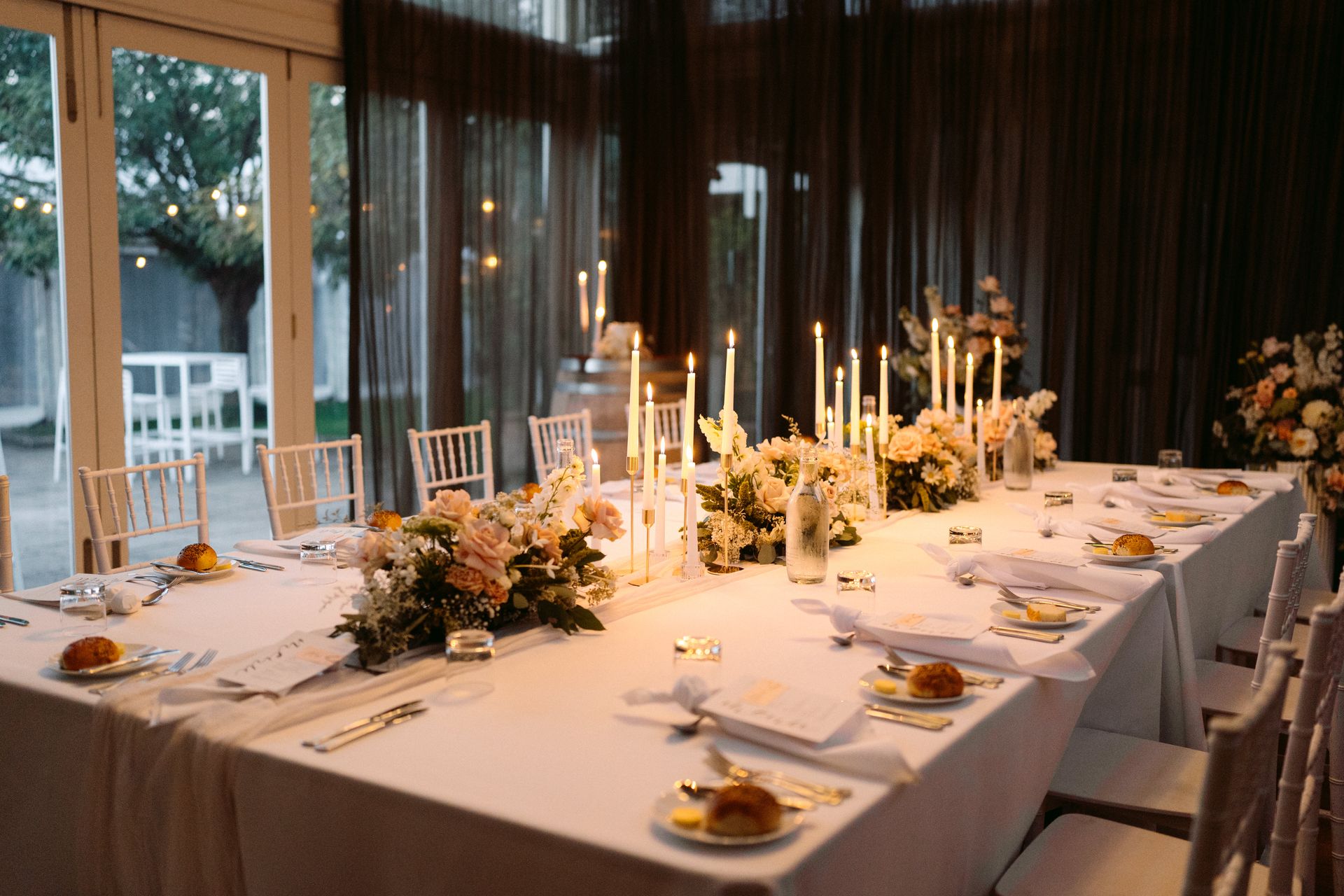 Formal dining table set for a wedding reception with flowers, candles, and white linens.