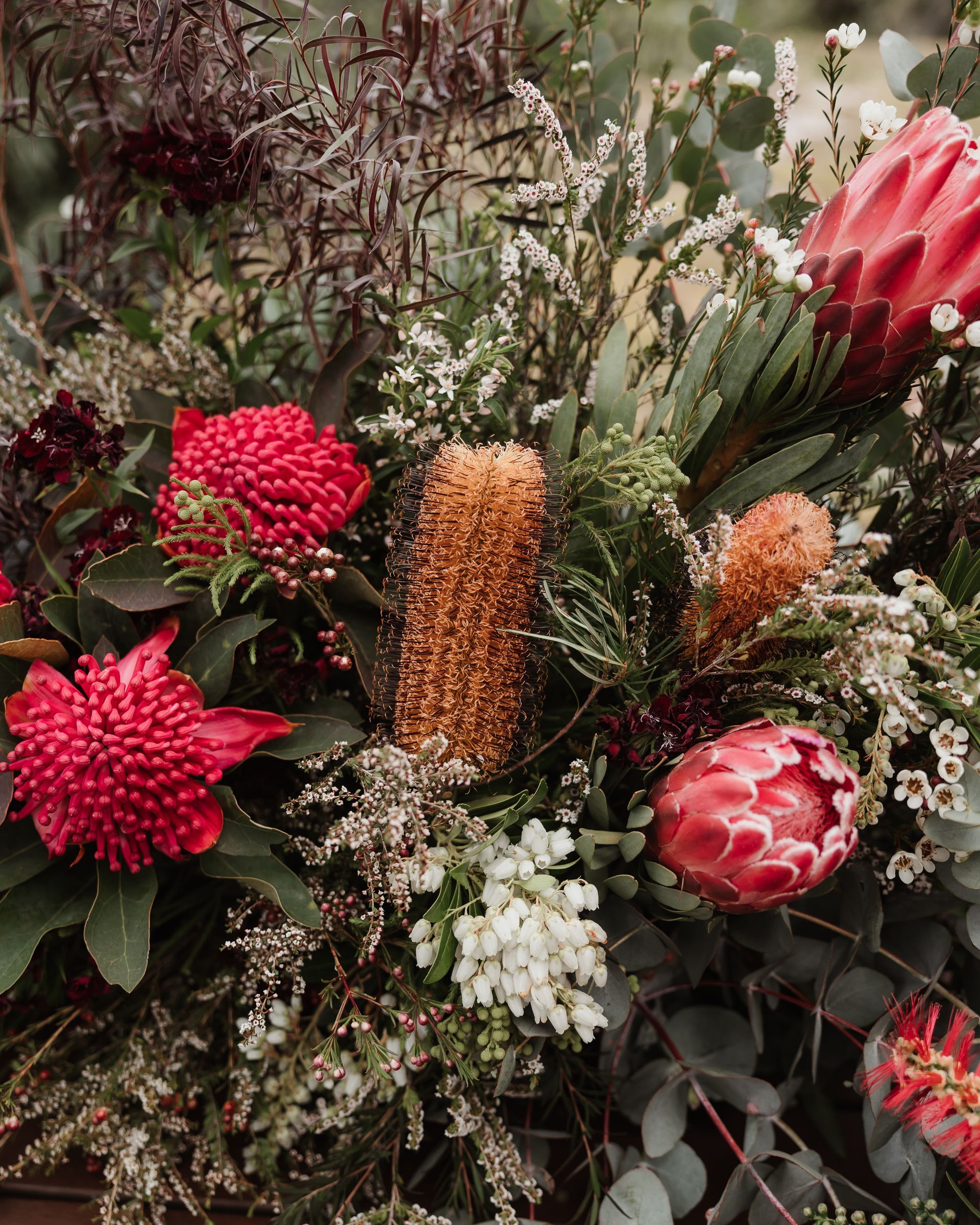 Arrangement of red and orange wildflowers and green foliage.