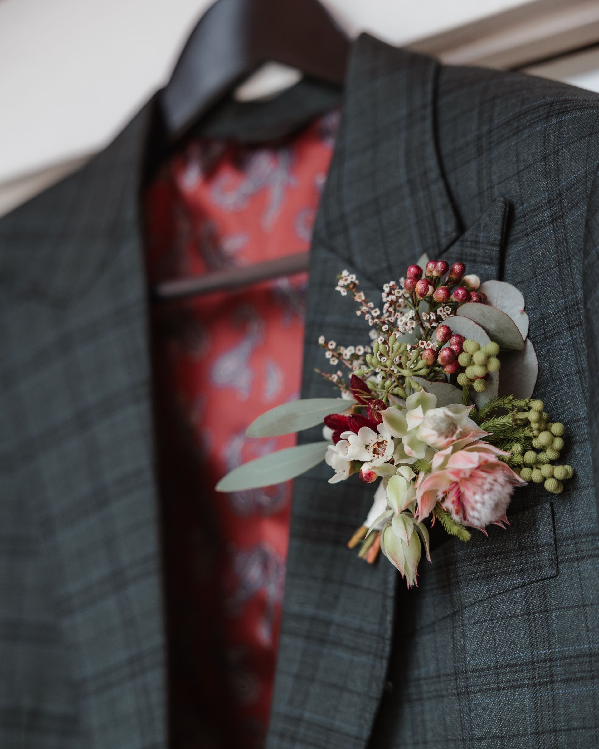 Dark green plaid blazer with floral boutonniere, red patterned lining.