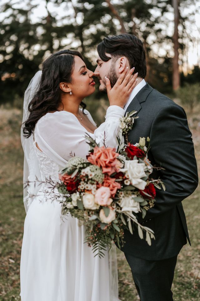 Bouquet of blush roses, white dahlias, and daisies with greenery on a wooden surface.