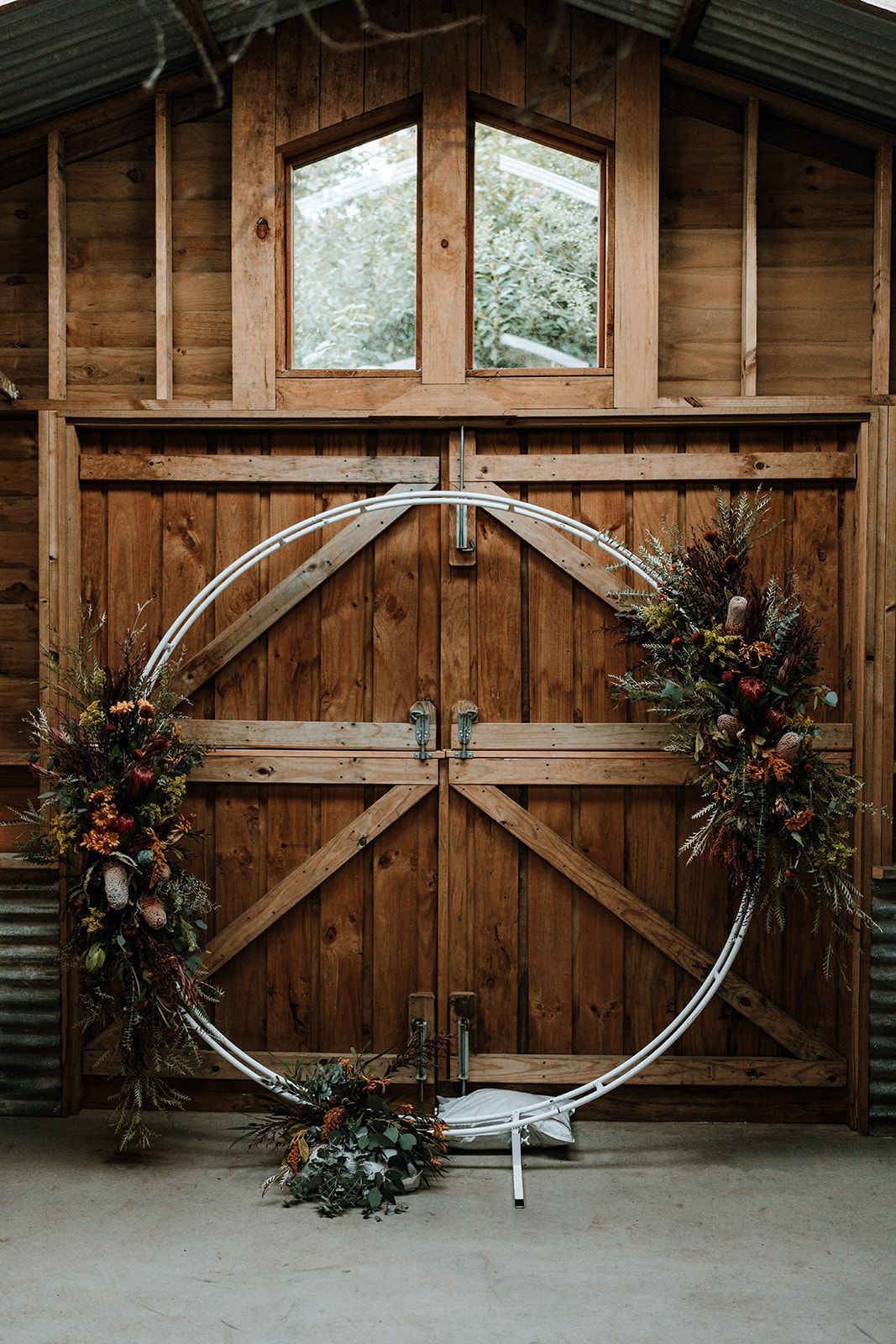 Large floral hoop decoration in front of a barn door. Autumn flowers, wood background.
