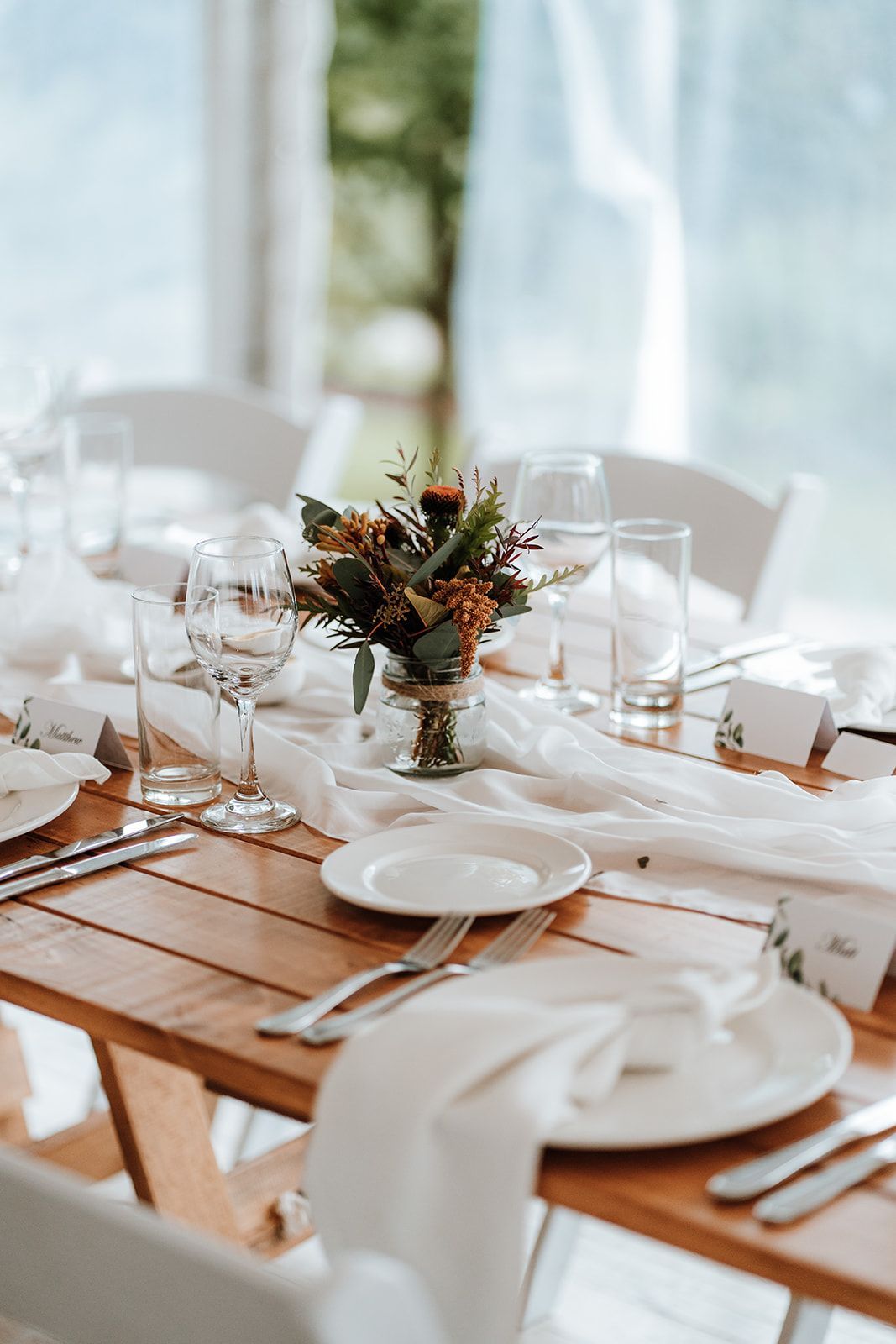 Wedding table setting with floral centerpiece, white linen, and glassware.