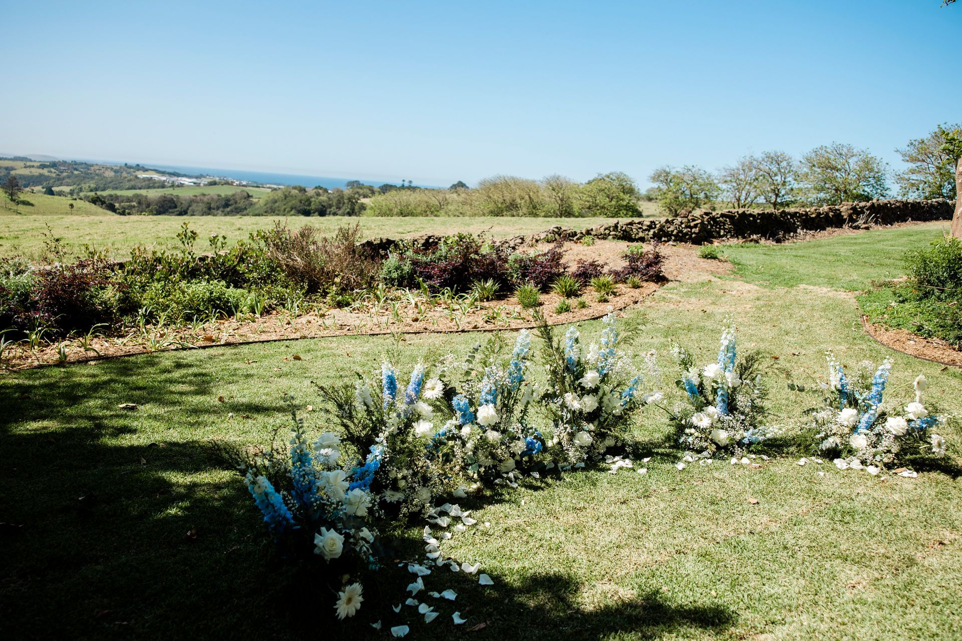 Floral arrangement in a grassy field with a scenic countryside view under a blue sky.