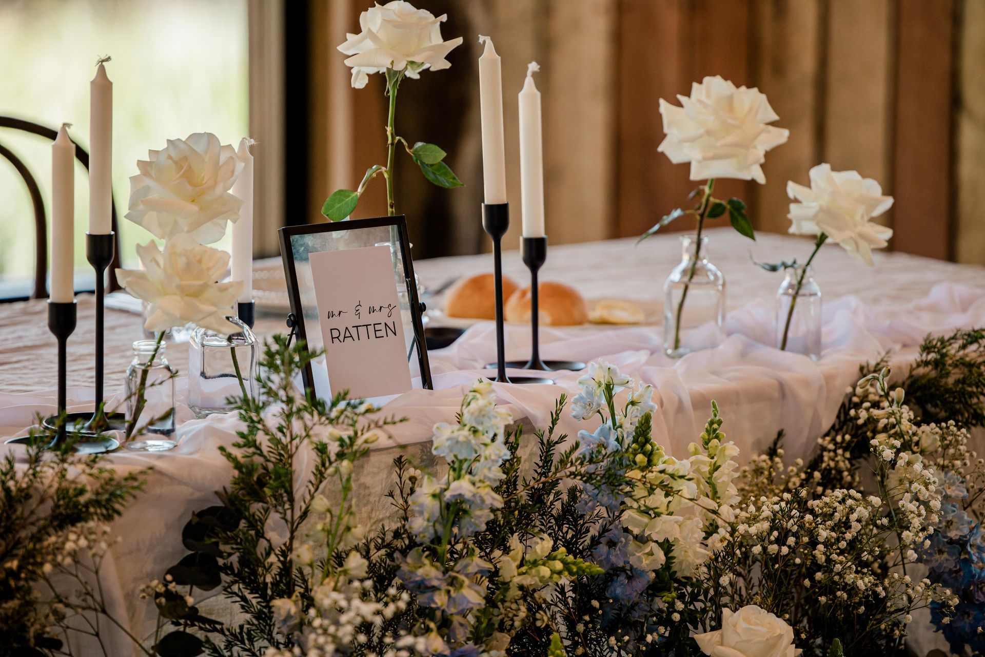 Elegant table setting with white flowers, candles, and a menu.
