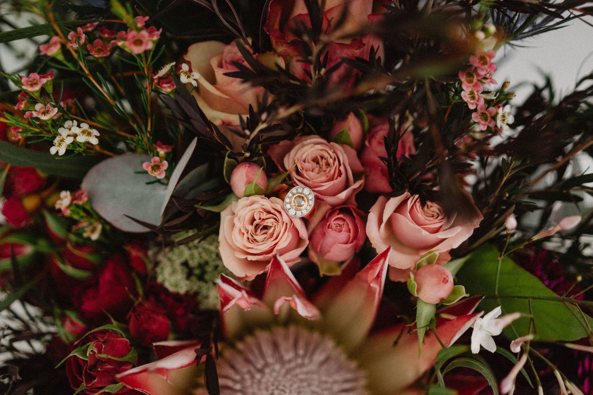 Close-up of a bouquet with pink roses and a ring nestled among the flowers.