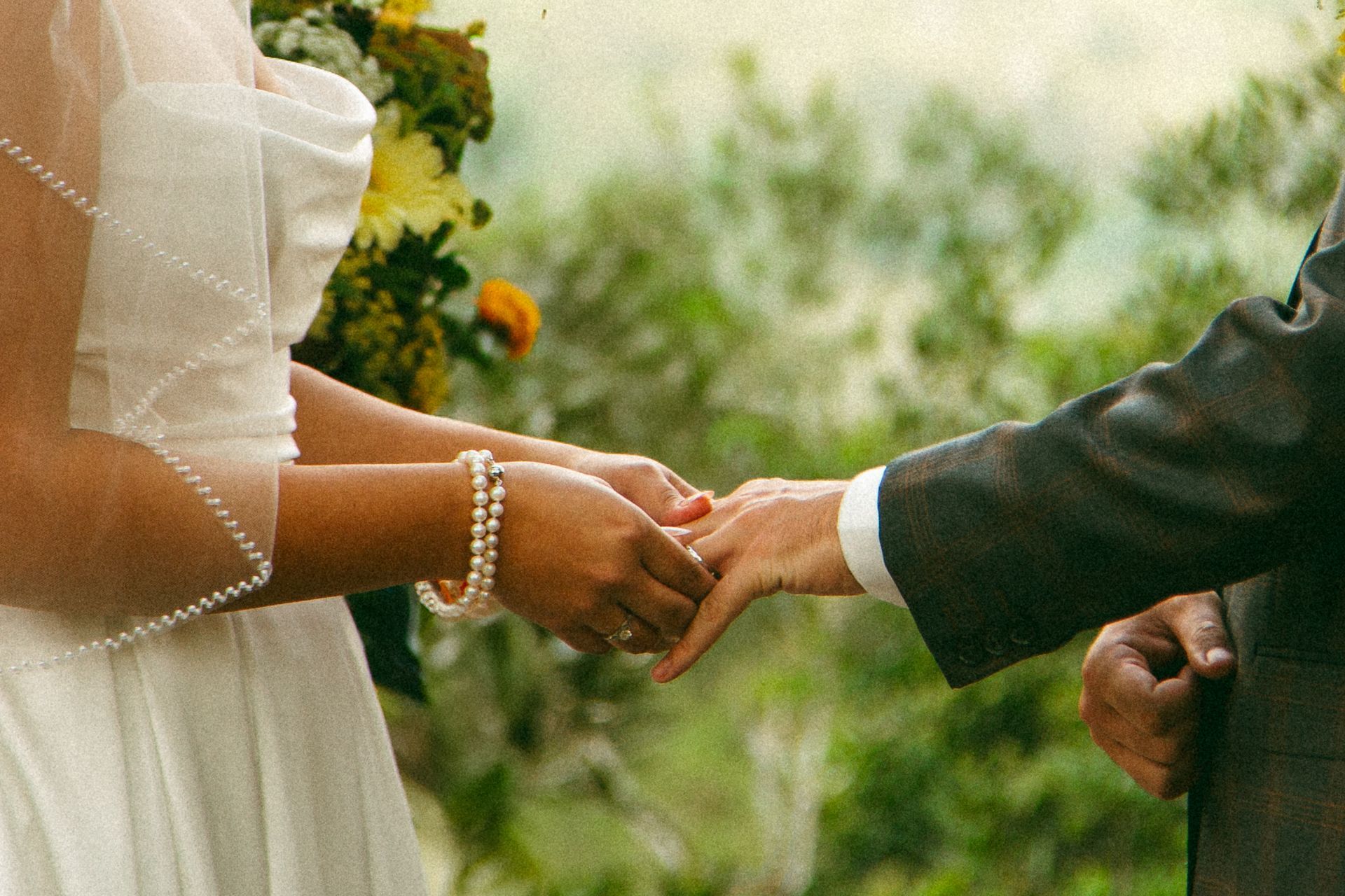 Bride and groom exchanging rings during outdoor wedding ceremony.