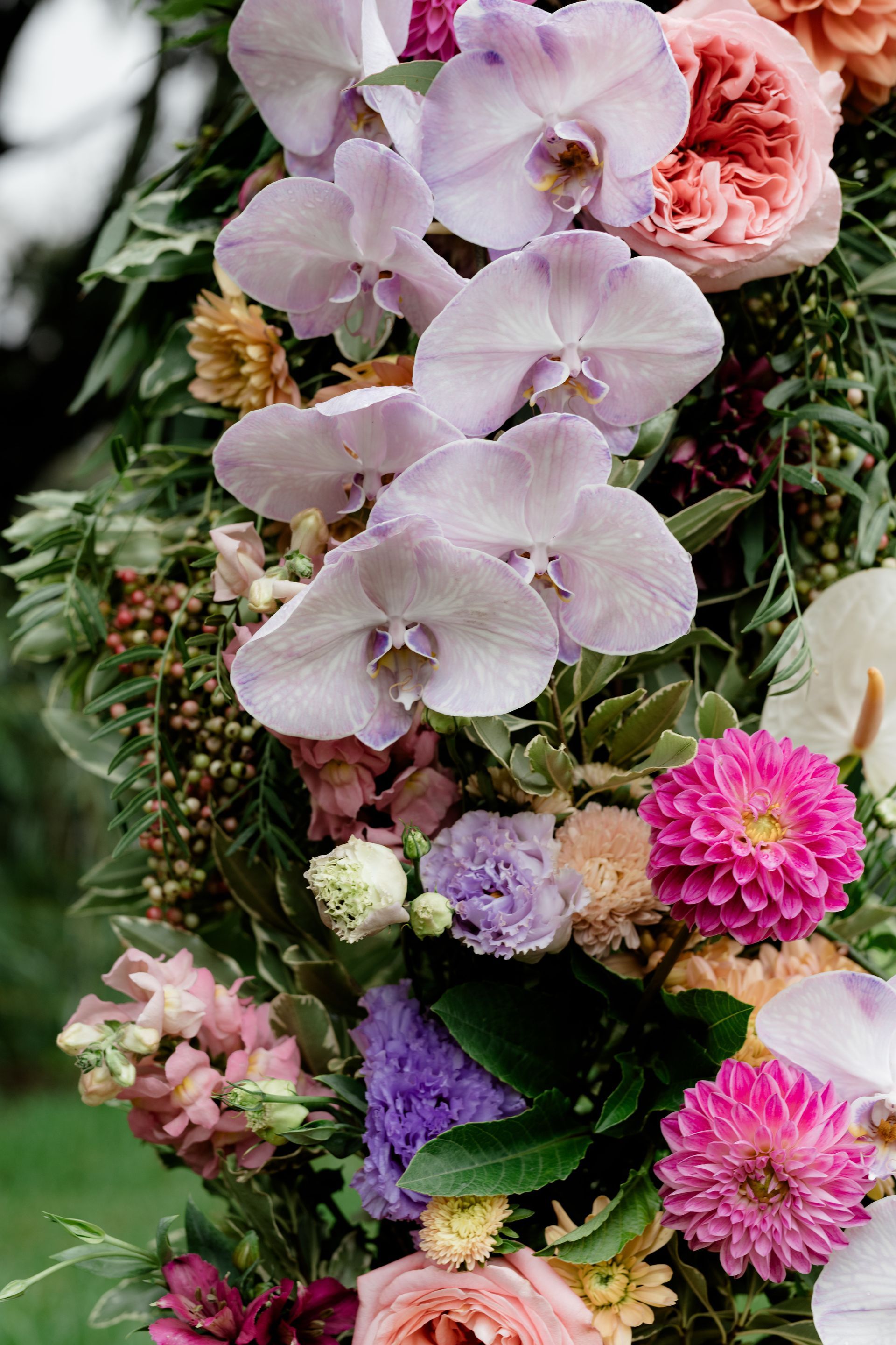 Floral arrangement with lavender orchids, pink dahlias, and peach roses.