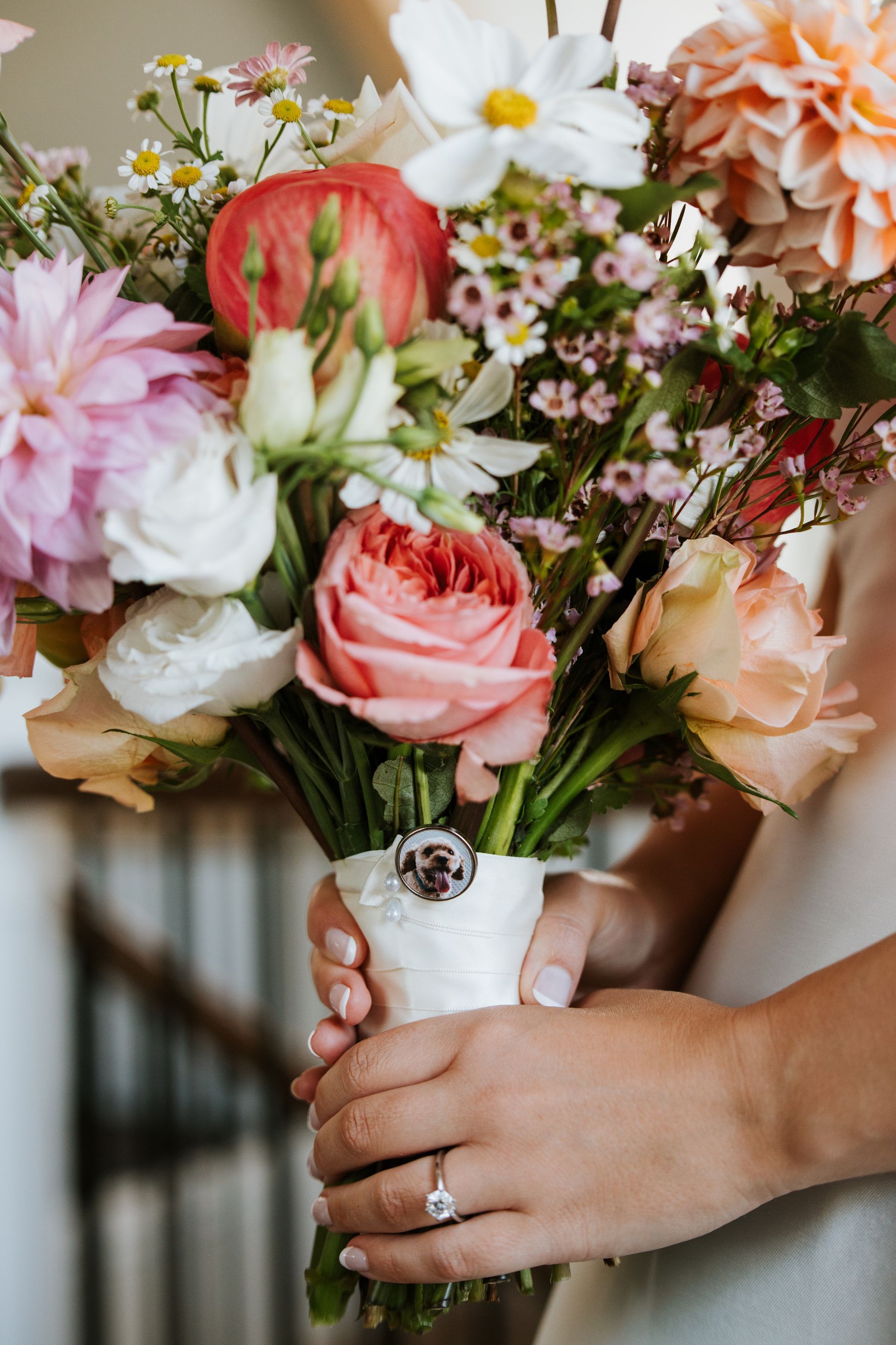 Woman holding colorful bouquet with engagement ring.