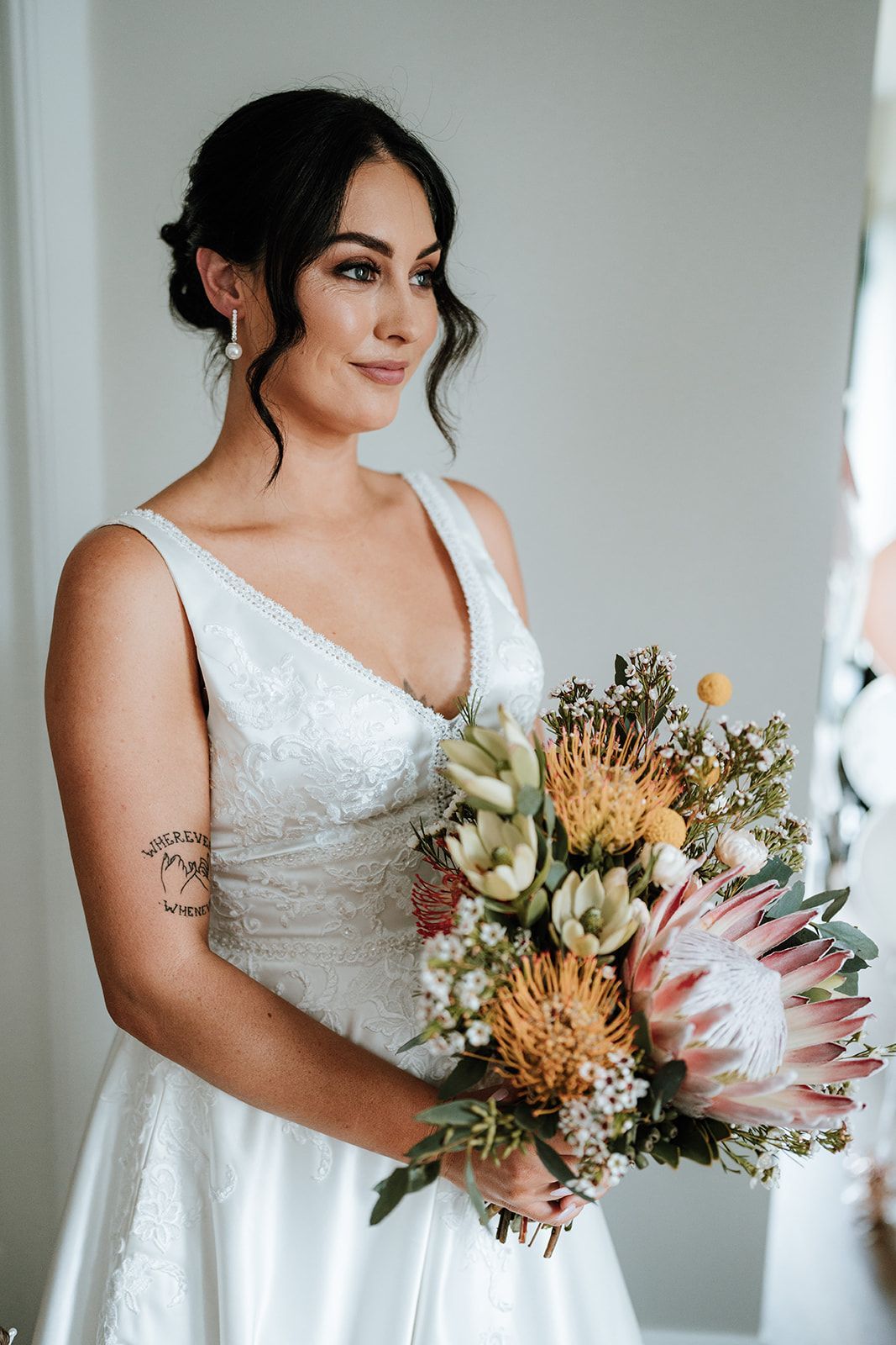 Bride in white dress, holding bouquet, looking to the side.