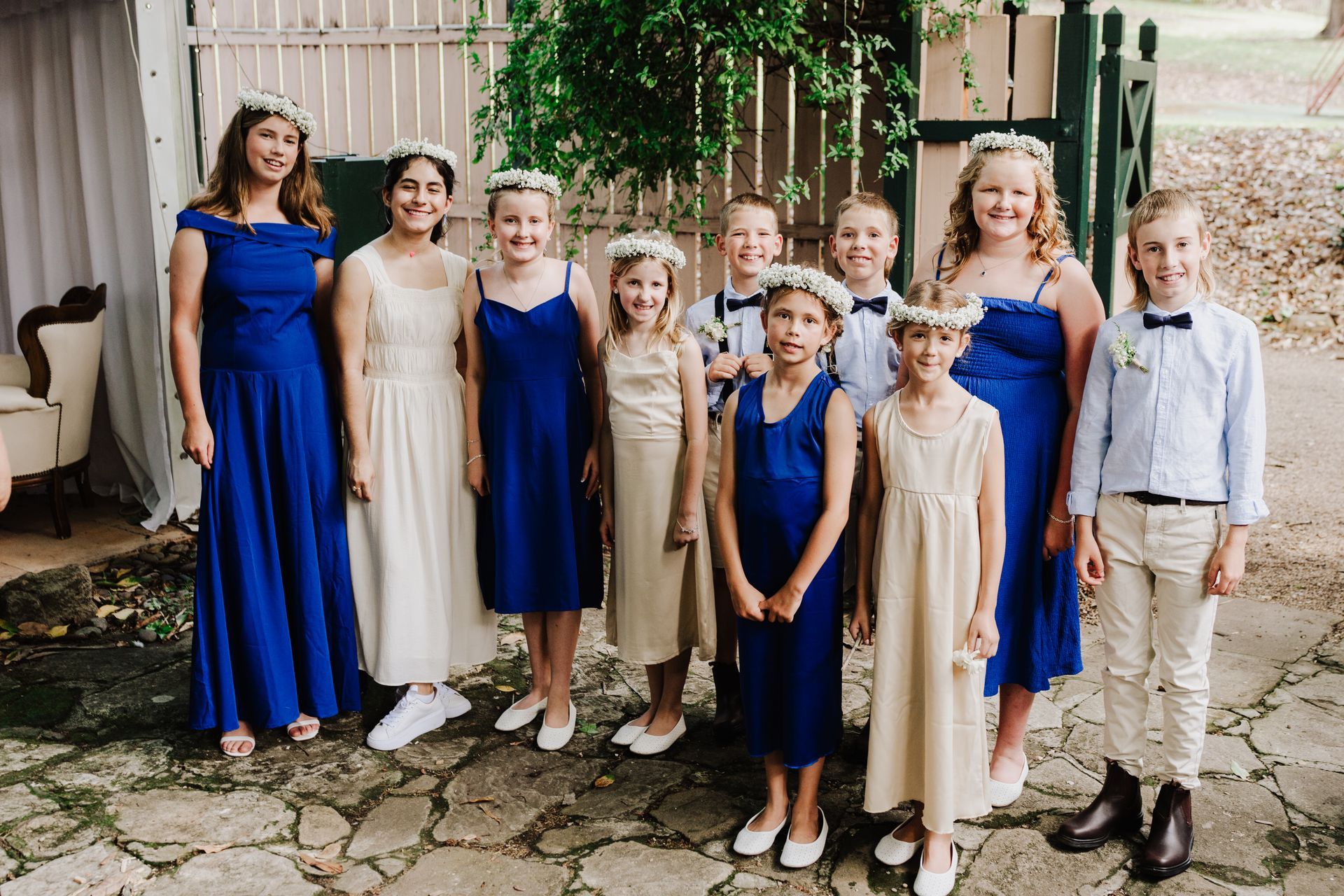 Wedding party, nine children and adults wearing blue and cream clothing posing togehter