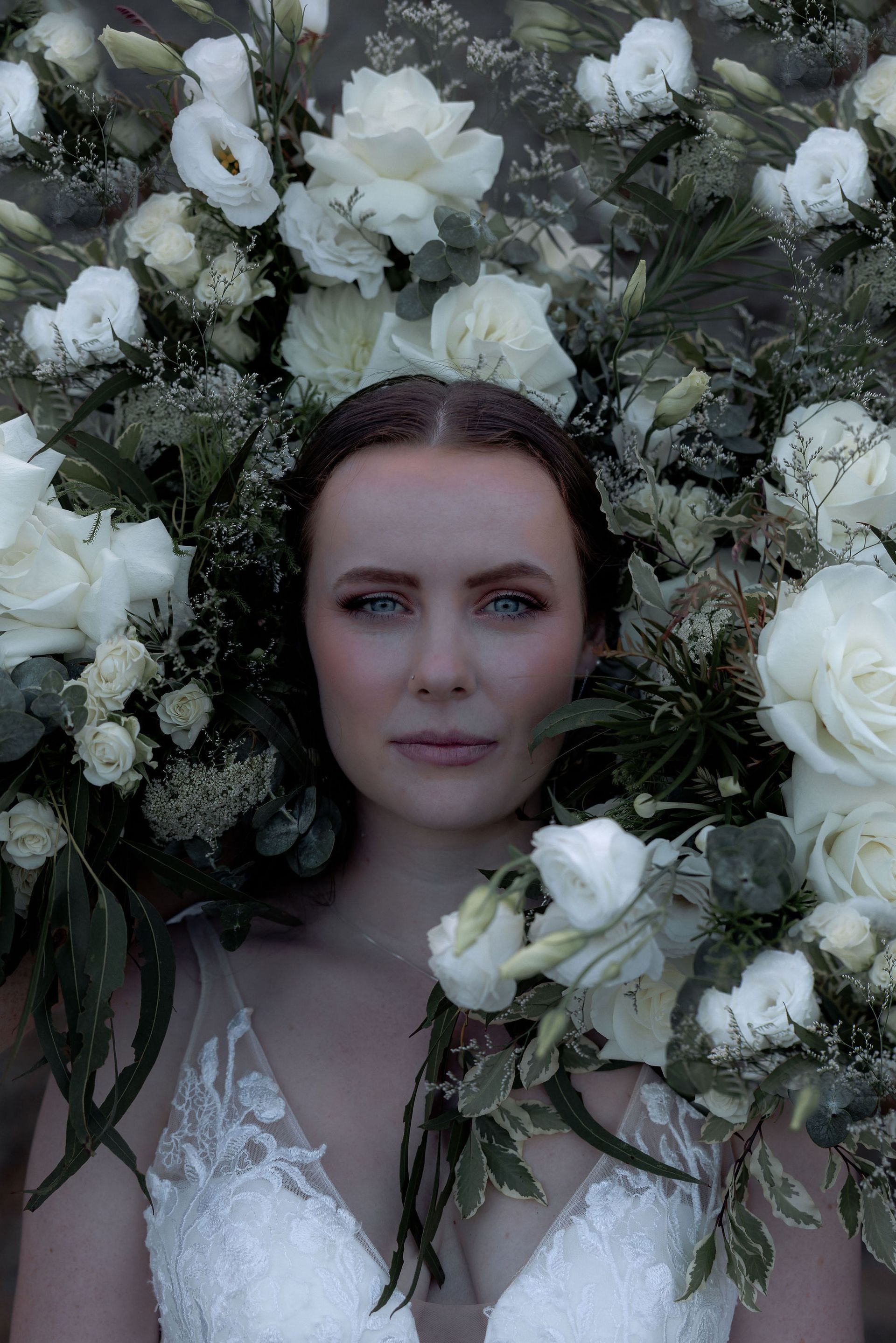 Woman with pale skin and floral arrangement, wearing a white dress with a deep V.