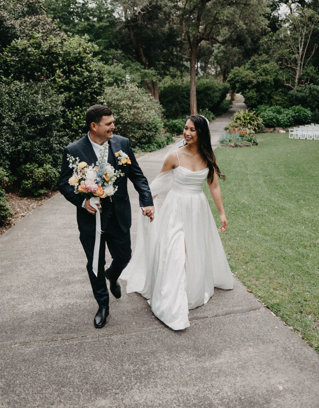 Bride and groom kissing in front of a floral arch and dark doors; barn setting.