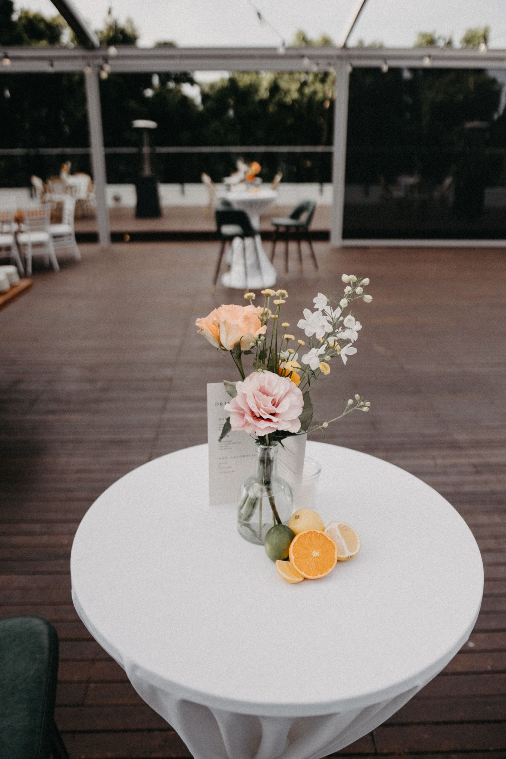 Small table with floral arrangement and orange slices, outdoor setting.