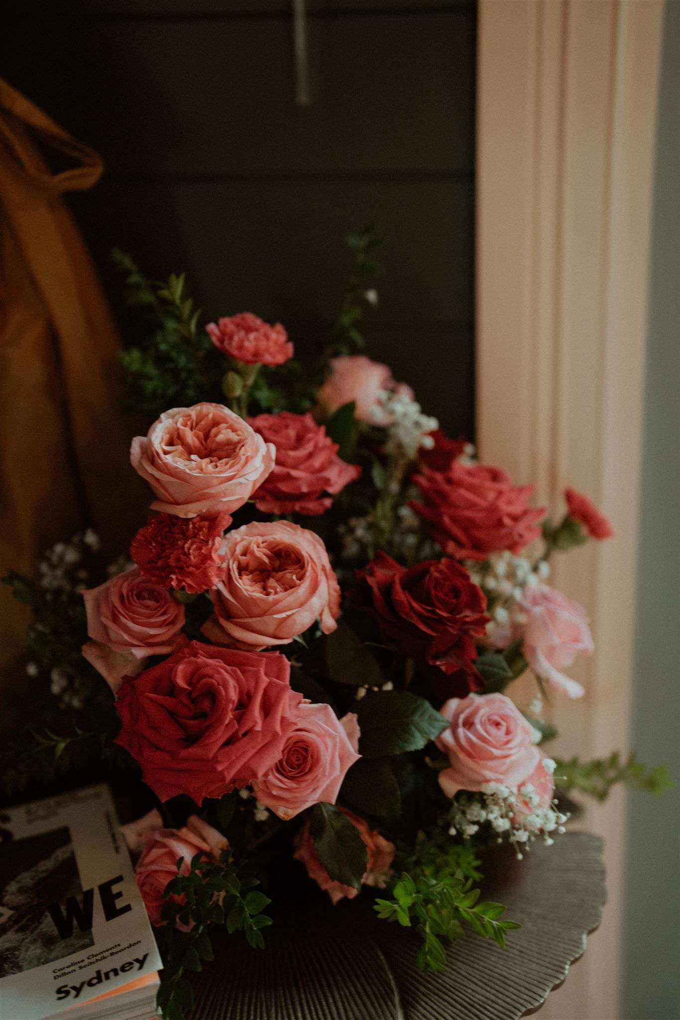 Bouquet of pink and red roses with greenery on a table.