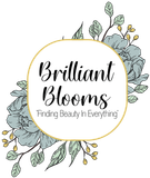 Brilliant Blooms logo with black script on a gold-outlined white oval, floral accents on either side.