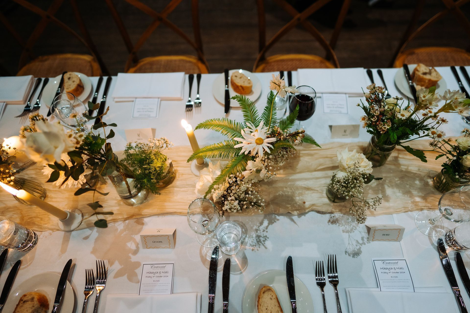 Wedding reception table setting with flowers, candles, and place settings.