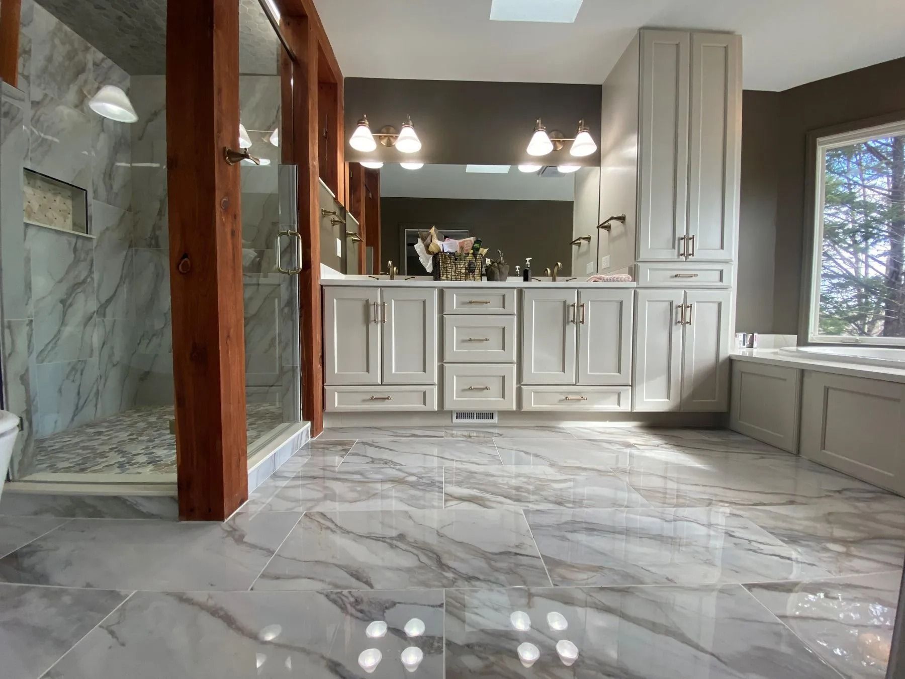 Spacious bathroom with marble floor, double vanity, large mirror, and walk-in shower.