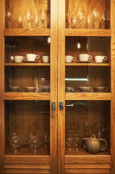 A wooden cabinet with glass doors filled with cups and glasses