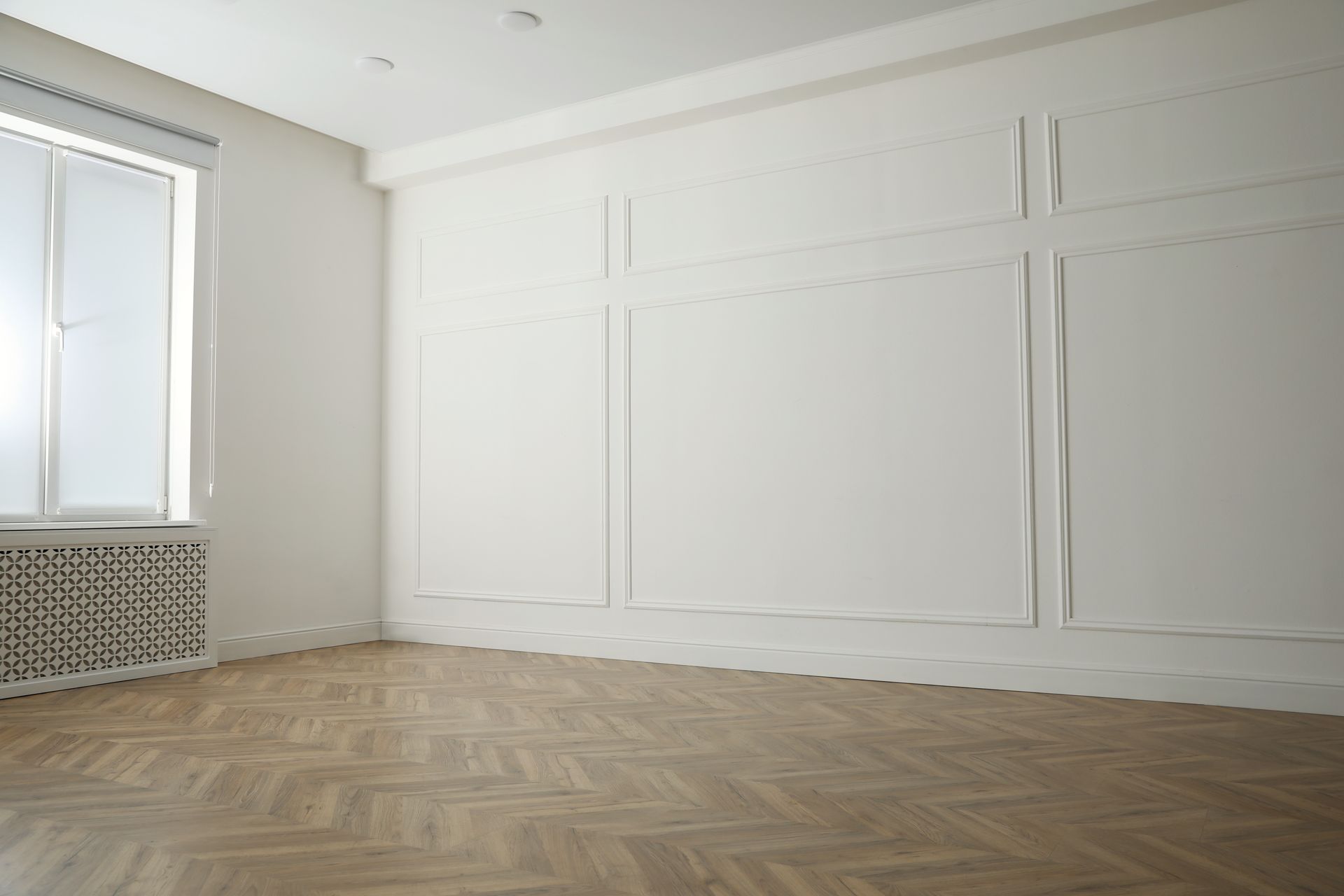 An empty room with a wooden floor and white walls.