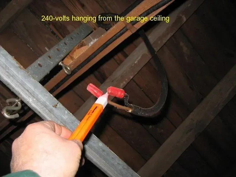 240 volts hanging from the garage ceiling with a person holding a pencil