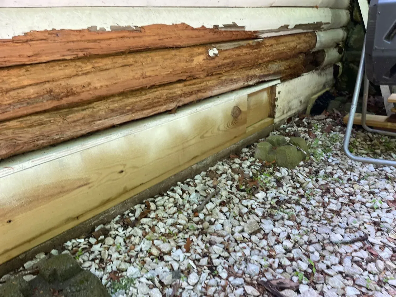 A log cabin is sitting on top of a pile of gravel.