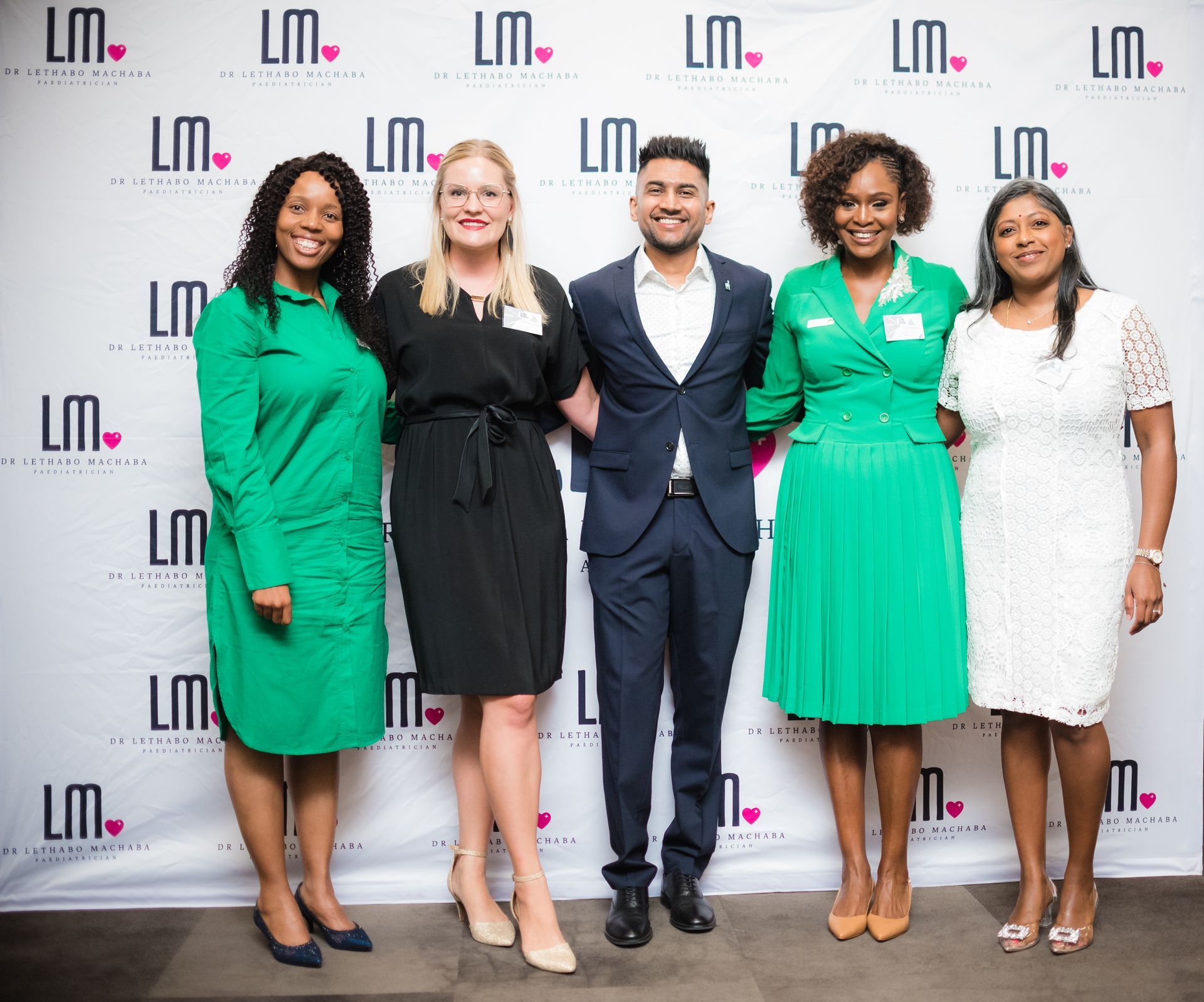 Five people, three women and two men, standing in front of a backdrop with logos.