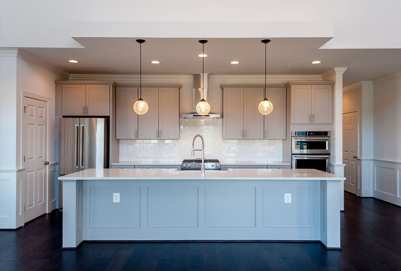 A kitchen with a large island , stainless steel appliances , and gray cabinets.