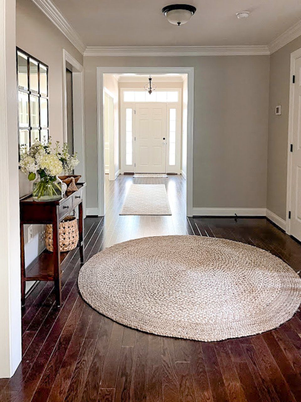 There is a round rug in the middle of the hallway.