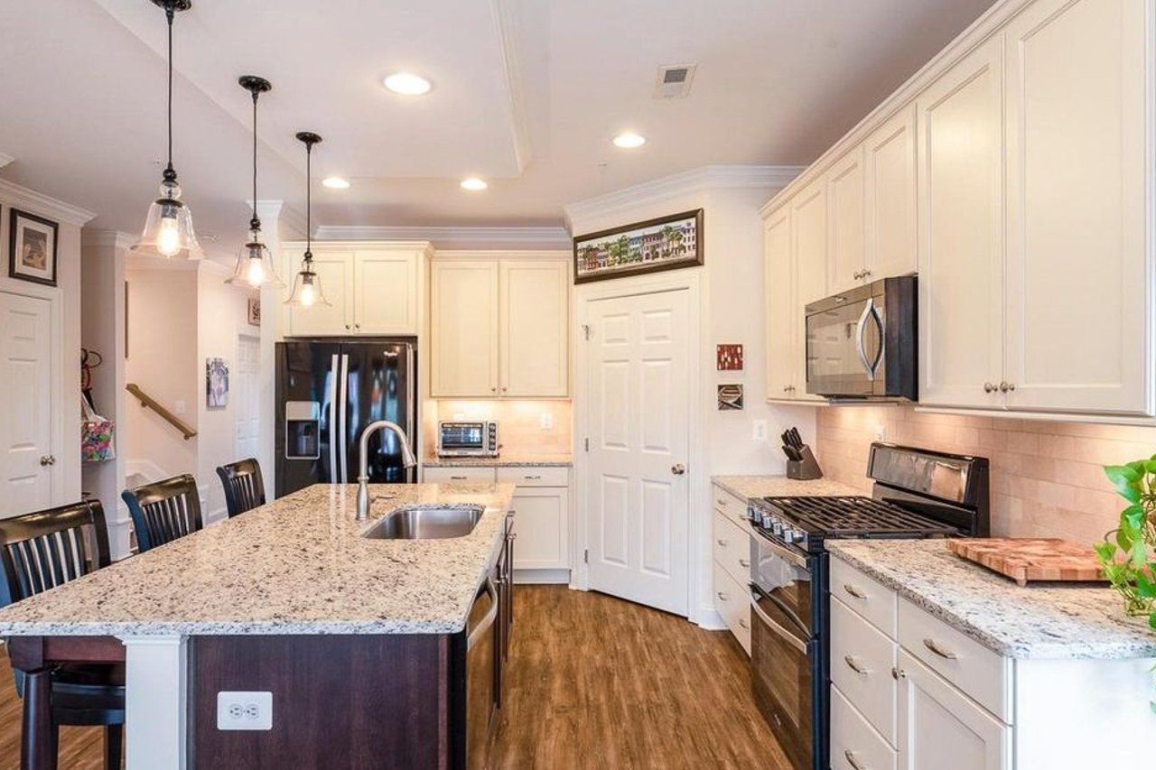 A kitchen with white cabinets , granite counter tops , stainless steel appliances and a large island.