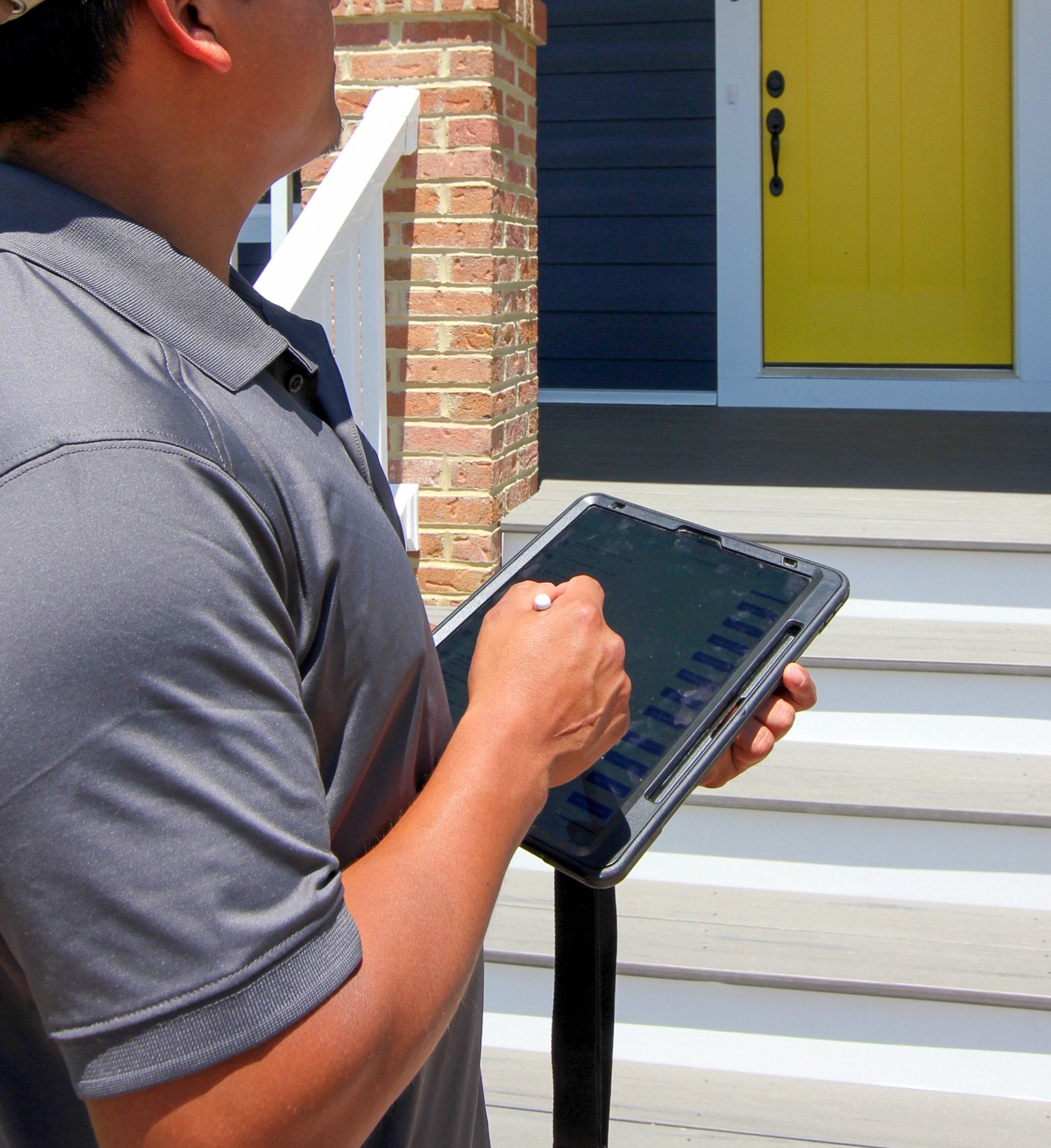 Man holding an ipad in front of home with yellow door | Build on Your Lot | Covell Communities | Chester, Maryland 21619