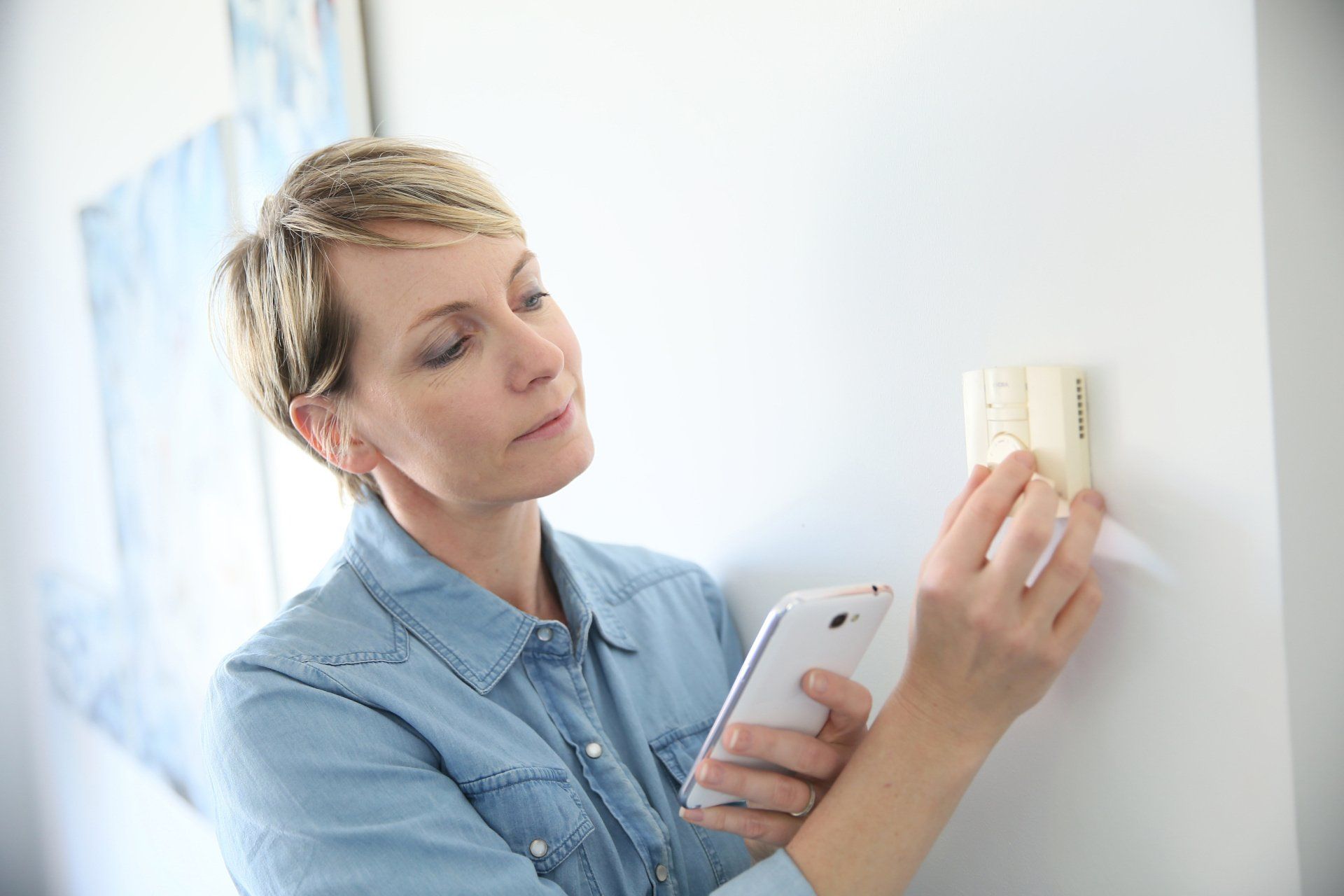 Woman making adjustments to thermostat | Build on Your Lot | Covell Communities | Chester, Maryland 21619