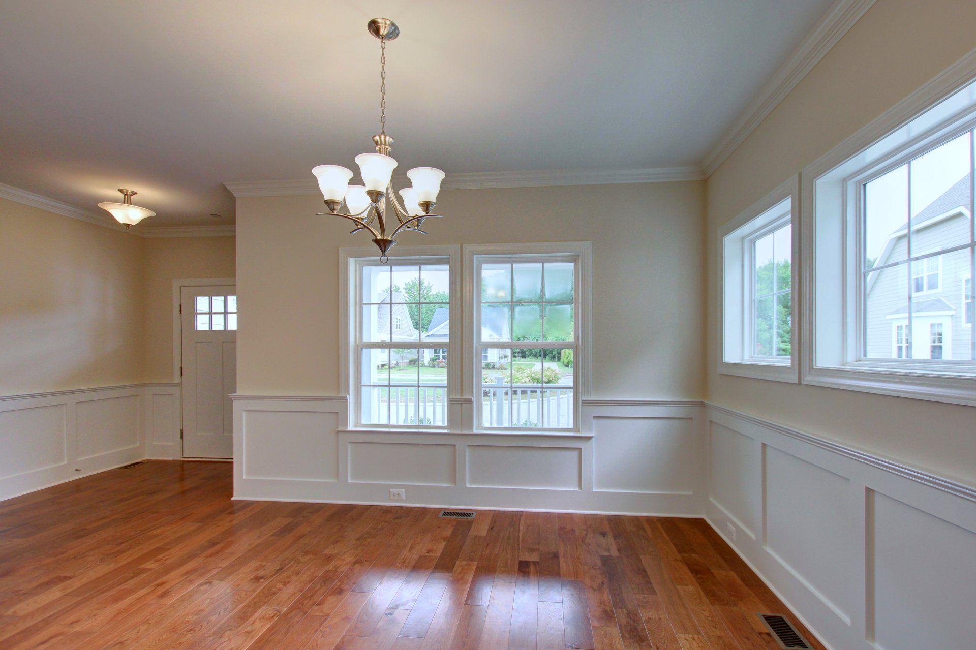 An empty dining room with hardwood floors and a chandelier