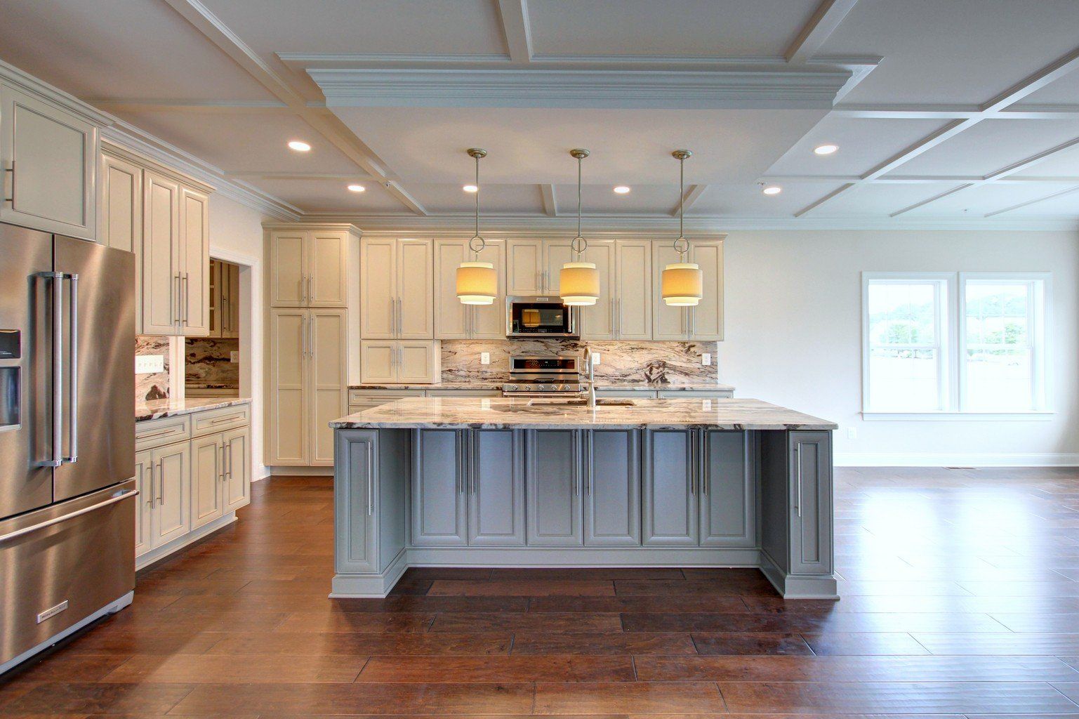 A kitchen with white cabinets , stainless steel appliances , and a large island.