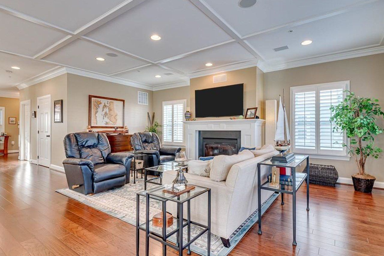 A living room with a couch , chairs , a fireplace and a flat screen tv.
