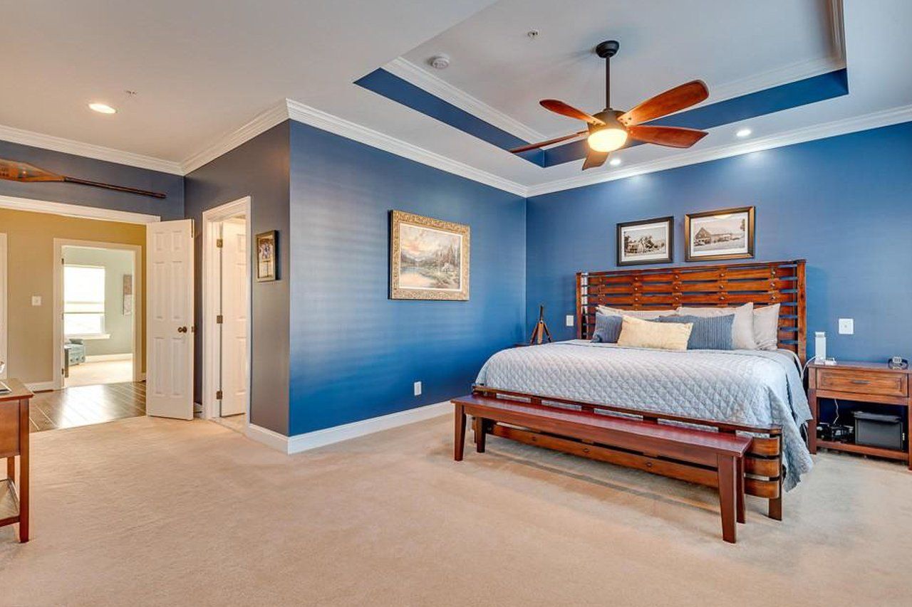 A bedroom with blue walls and a ceiling fan.