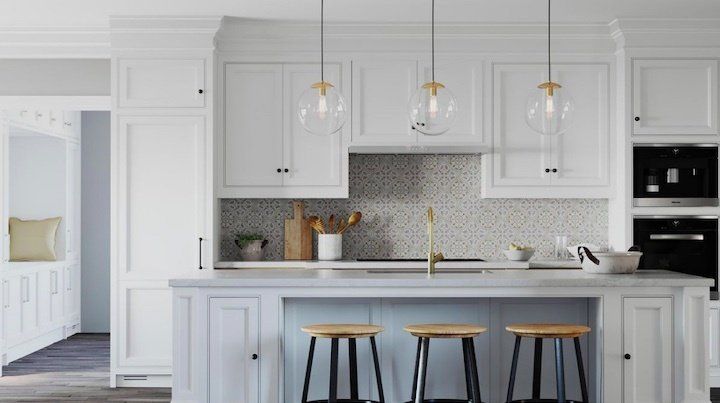 A kitchen with white cabinets and a blue island with three stools.