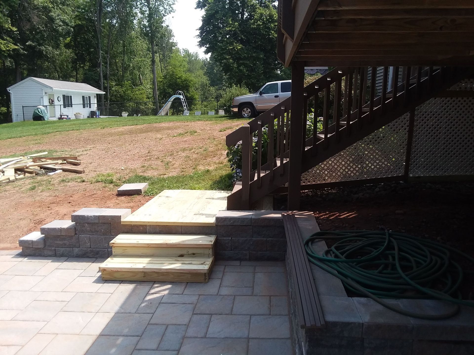 A hose sits on a patio next to a deck