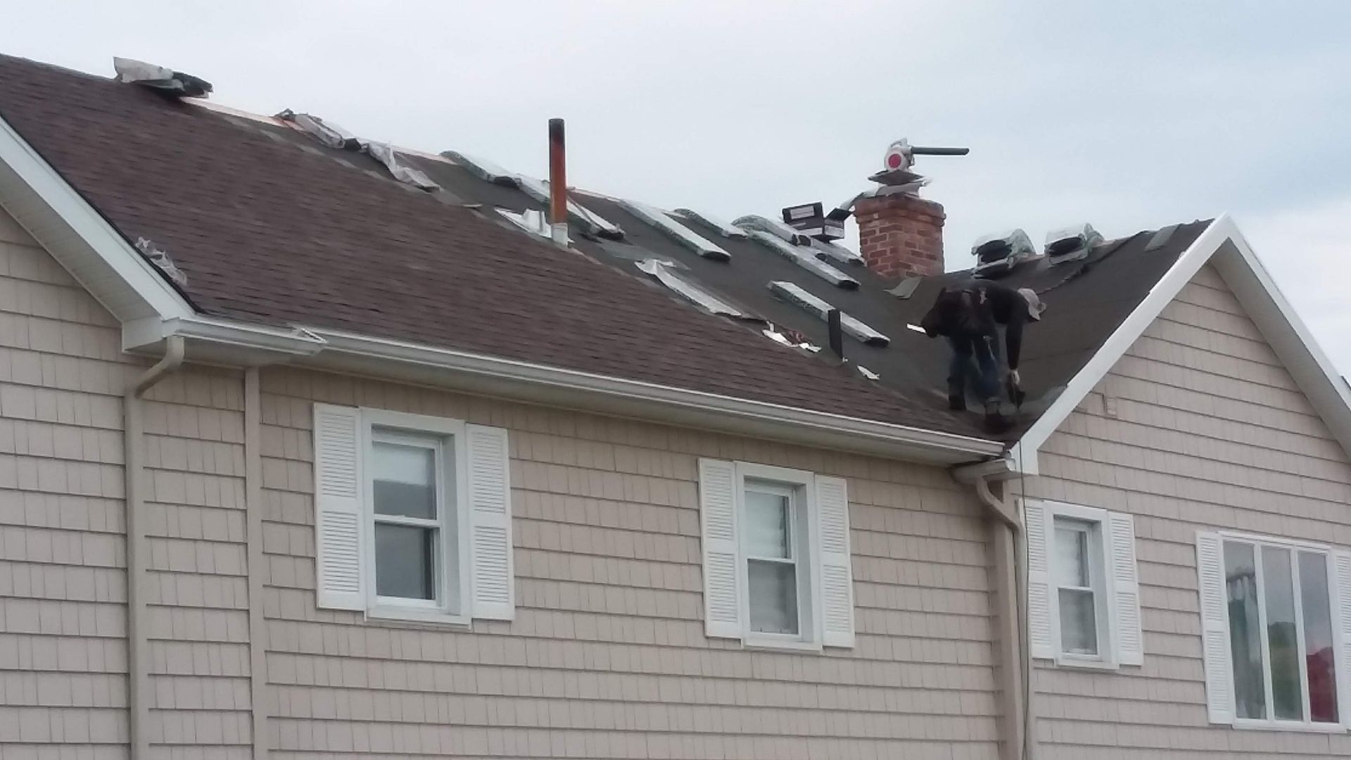 Two men are working on the roof of a house
