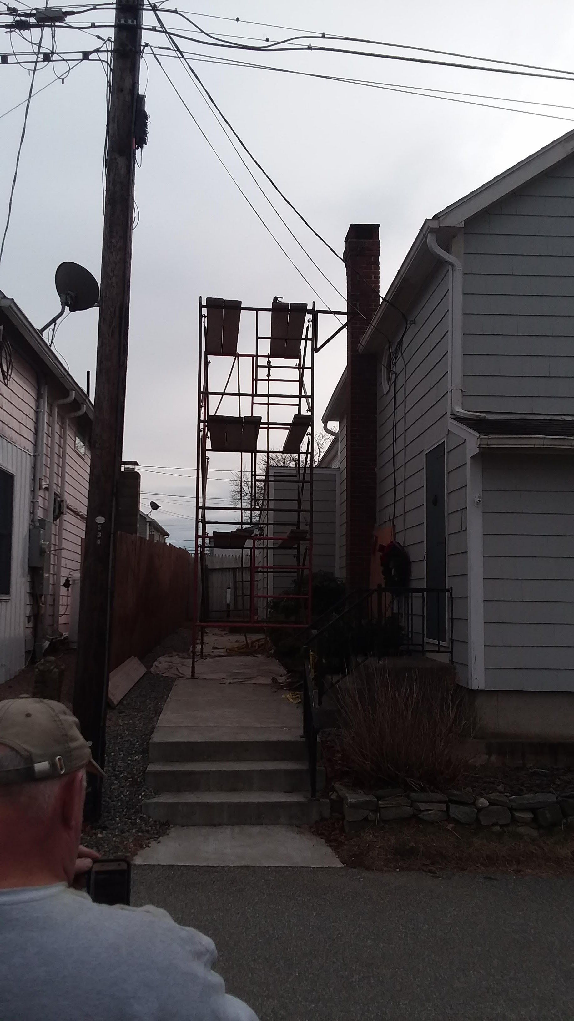 A narrow alleyway between two houses with a scaffolding in the middle