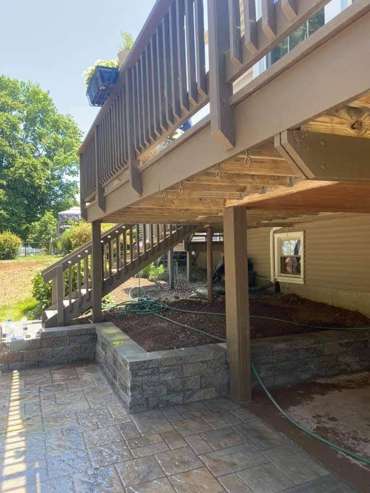 A wooden deck with stairs leading up to it is under a house.