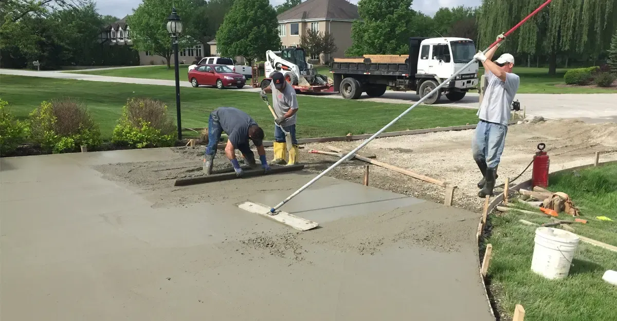 A group of men are working on a concrete driveway.