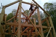 A large wooden structure is being built in the woods.